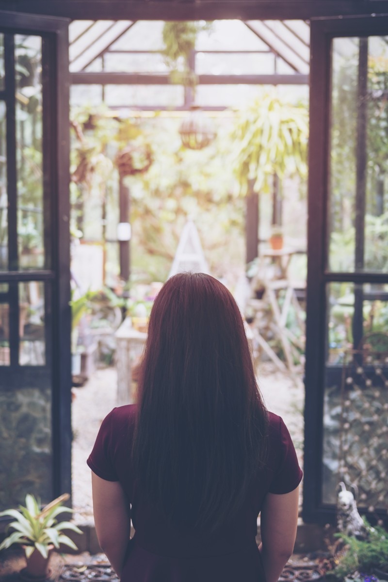 A lonley place, woman looking out through house to garden