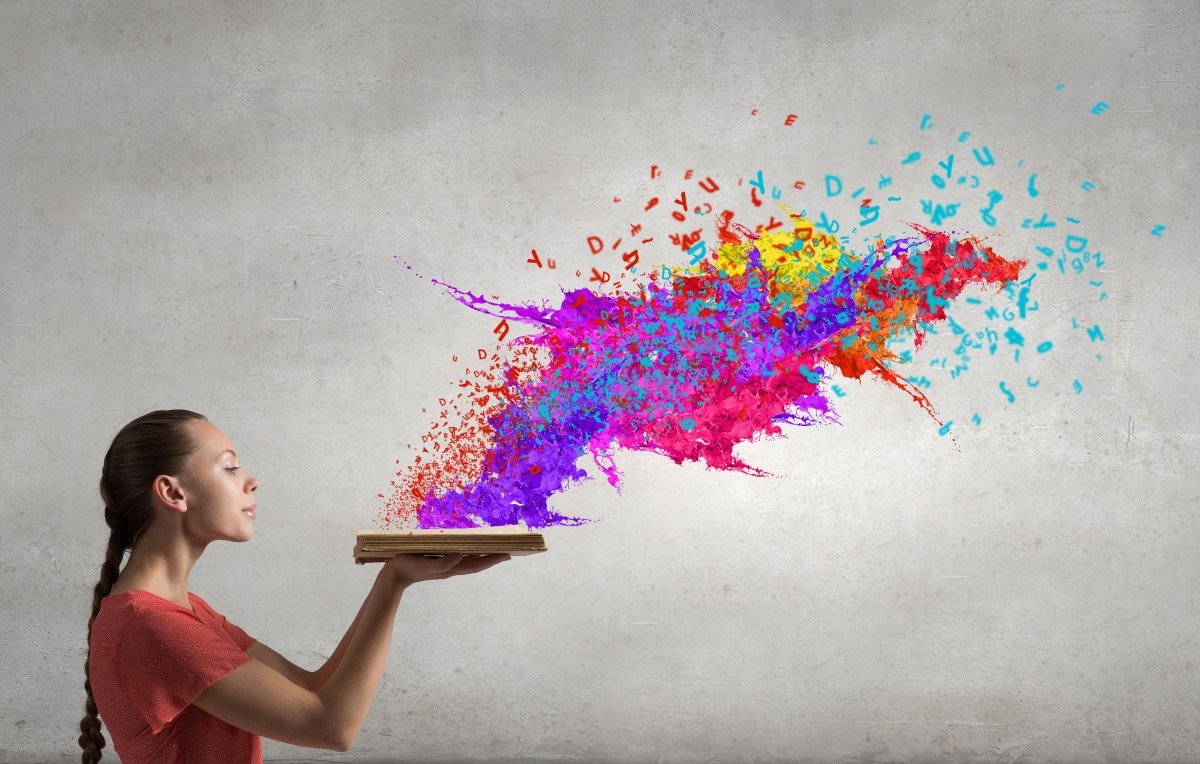 Young woman blowing multicoloured rainbow powder from a plate